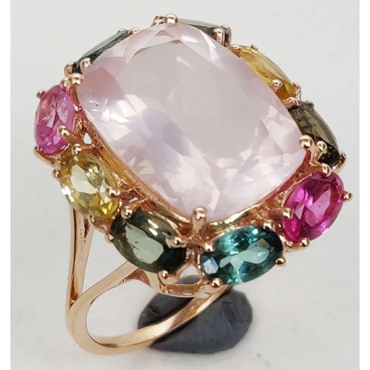 Silver Jewellery_page-0010 Gold-tone silver ring featuring a large rose quartz center stone surrounded by multicolour gemstones in an elegant statement design.